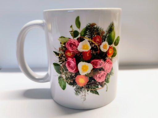 Weißer Becher mit buntem Blumenstrauß und Eiern als Dekor.